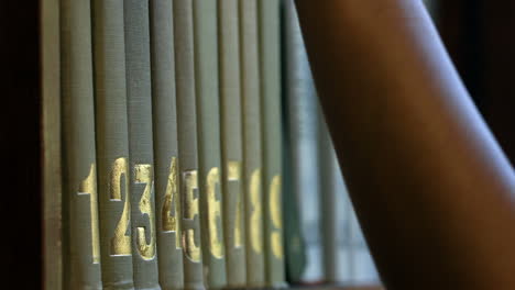 estudiante recogiendo un libro del estante en la biblioteca