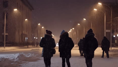 people walking on a snowy street at night