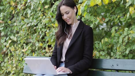 smiling woman using laptop in park