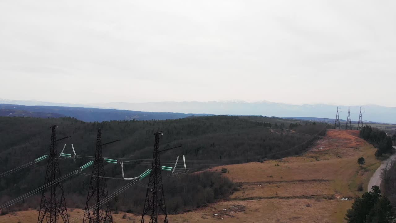 Aerial footage of electric high voltage power transmission towers on a field
