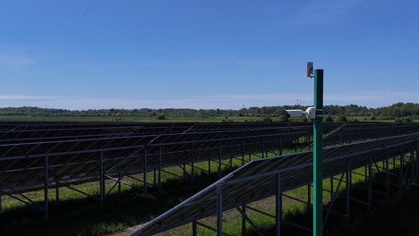 a security camera watches over a large solar panel farm under a clear blue sky