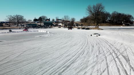 following a drifting car that is sliding on the ice track on a frozen lake aerial 4k drone at poynette wisconsin