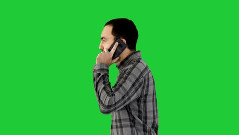 joven fresco con barba caminando y hablando con teléfono móvil en una pantalla verde, clave de croma