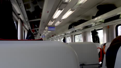 pov inside train carriage behind rows of seats at it travels past landscape