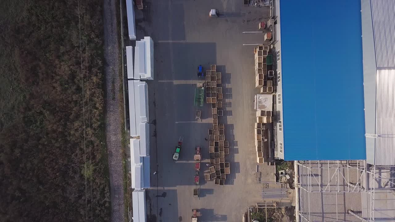 two loaders are transporting pallets with apples in the warehouse for the subsequent transportation of apples to the factory. Aerial view