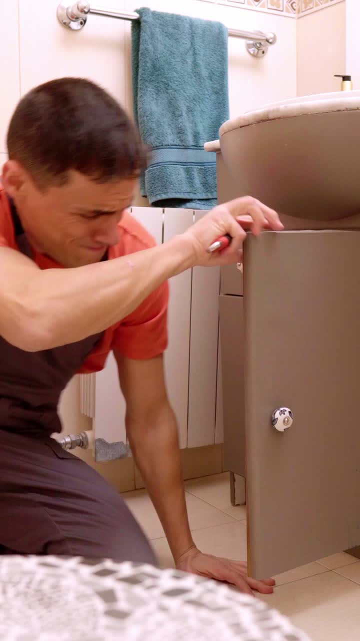 Plumber inspecting and repairing bathroom sink cabinet
