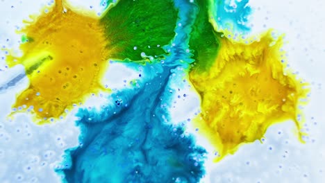 bright yellow and blue ink drops in water with a bubbling effect, high-angle shot