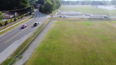 drone tracks a truck on a road near a field.