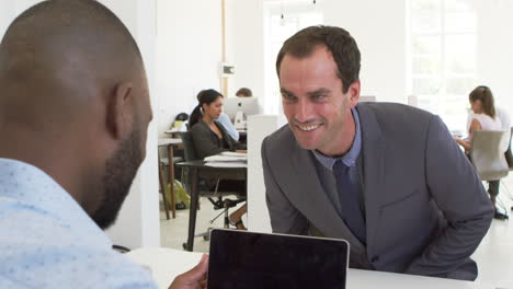 two men shake hands before an interview in open plan office