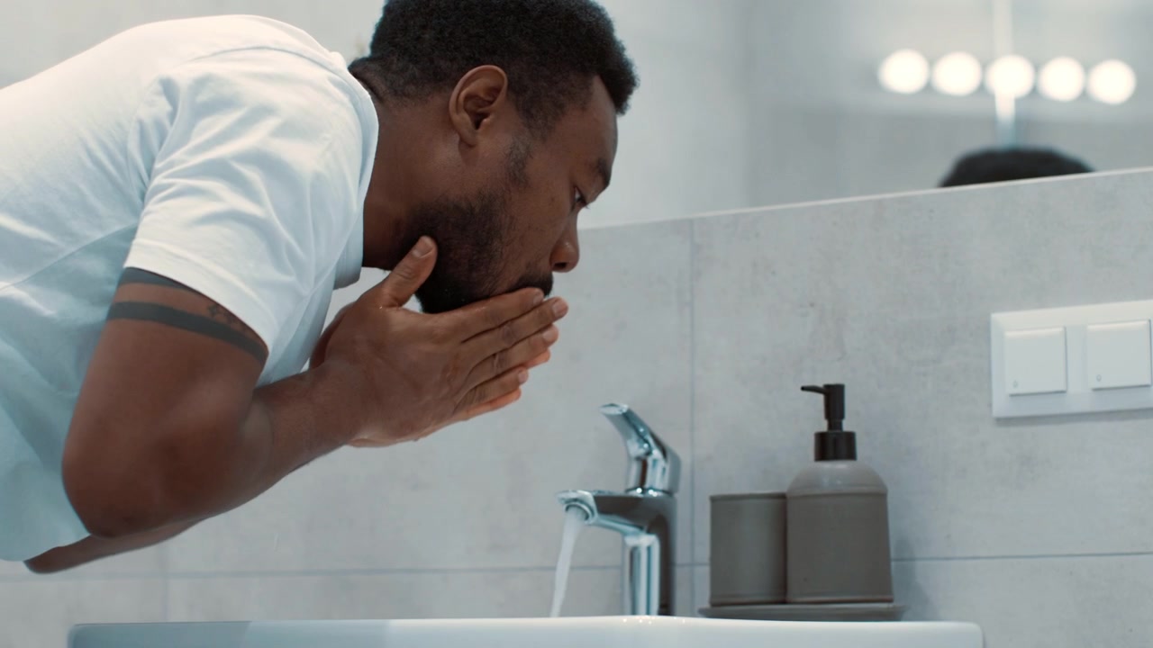 Young Man Washing His Face in a Modern Bathroom