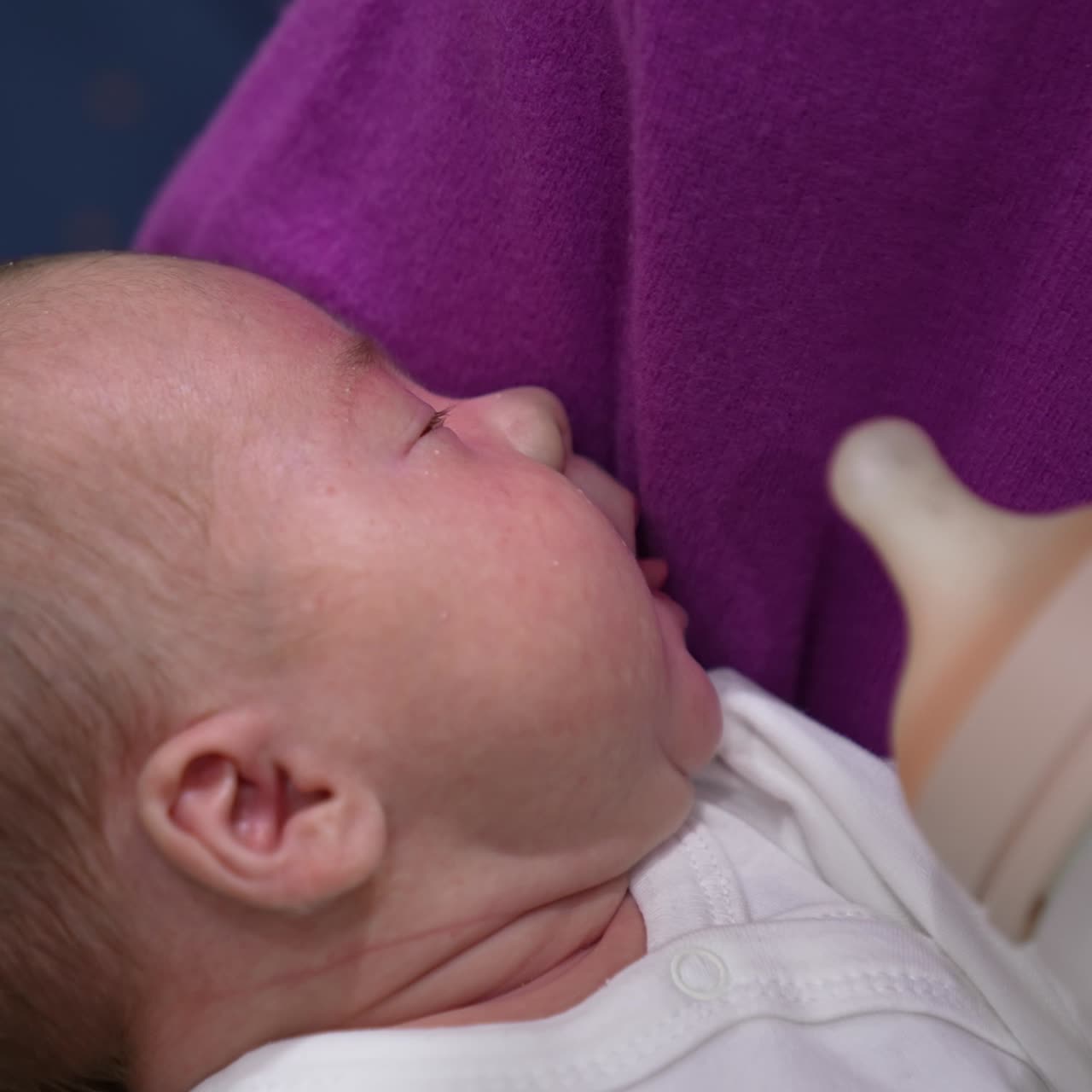 Bebê fofo está com fome e abrindo a boca pronto para comer. Mãe carinhosa dá uma mamadeira ao bebê. O bebê pega a mamadeira de leite.