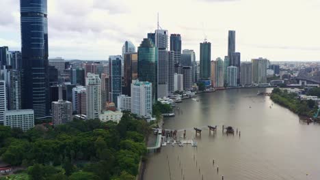 vista aérea drone sobrevolando el río brisbane capturando el paisaje urbano del centro de la ribera, edificios de gran altura y rascacielos en el distrito central de negocios, ciudad capital de queensland, australia