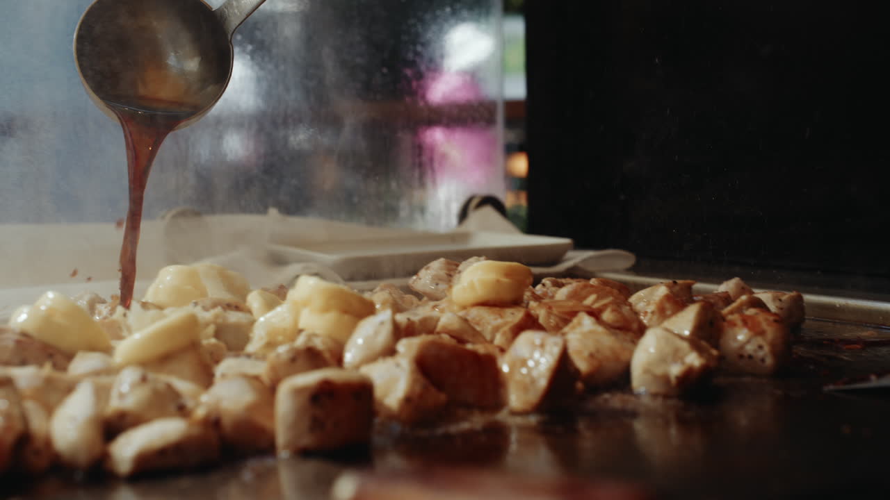 Versare salsa di soia su pollo teriyaki in uno stand di festival con un cucchiaio da minestra.