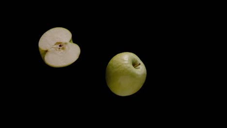 Cut-in-half-apple-falling-isolated-on-black-background,-super-slow-motion