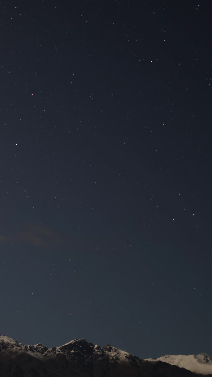 Langit malam yang tenang dengan bintang-bintang di atas pegunungan bersalju di Queenstown, Selandia Baru. Gerakan minimal, suasana jernih dan tenteram