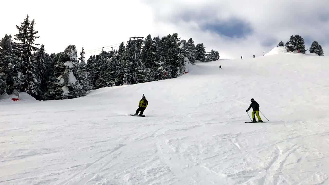 vista en cámara lenta de snowboard masculino adulto cuesta abajo de las montañas durante el día