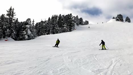 Zeitlupenansicht-Eines-Erwachsenen-Männlichen-Snowboarders,-Der-Tagsüber-Den-Hang-Der-Berge-Hinunterfährt
