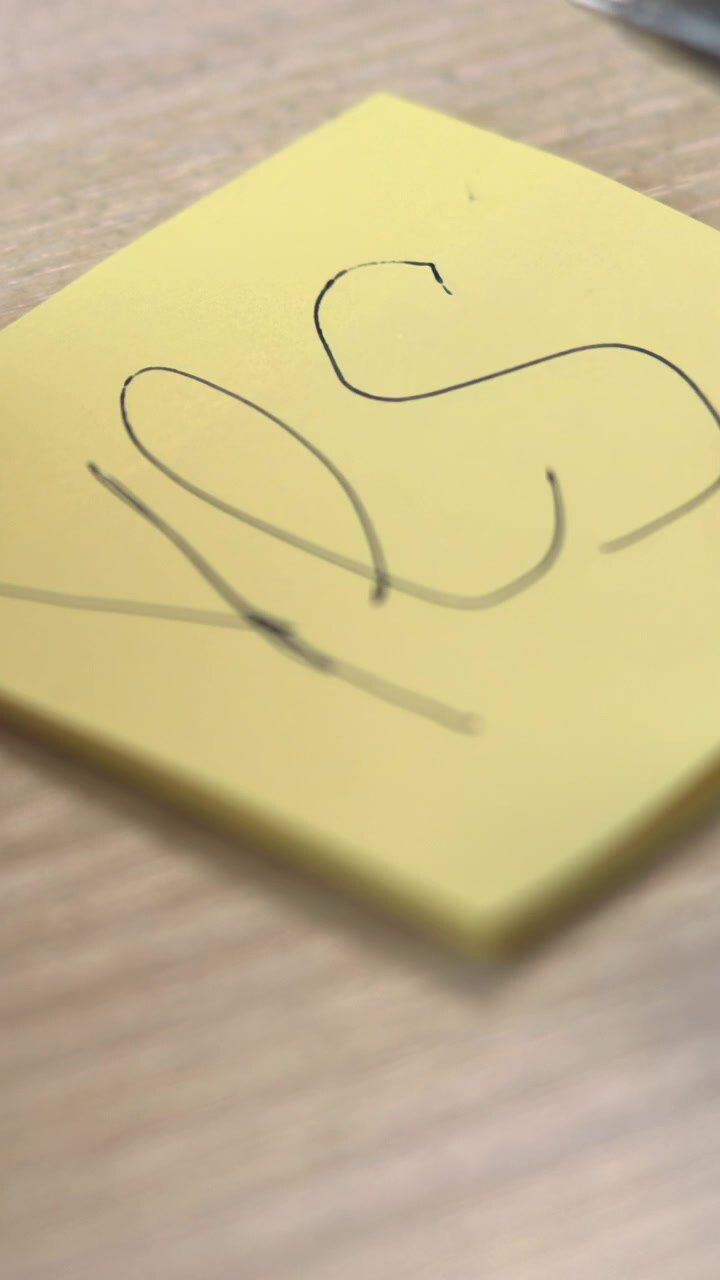 Closeup Of Hands Writing Bold Yes On Yellow Sticky Note, Decisive Pen Strokes, Wooden Desk Texture. Media