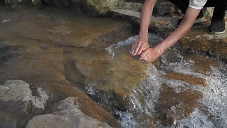 close-up of a person touching a flowing stream