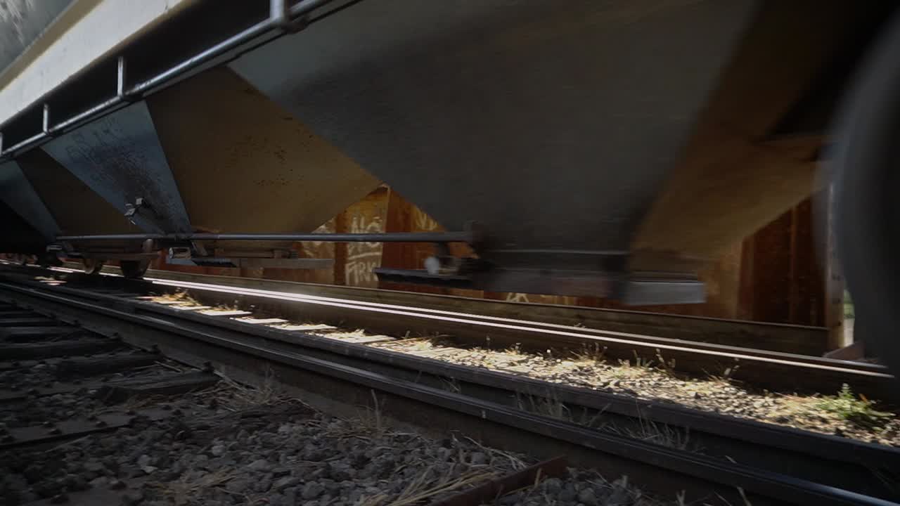 Panning closeup view of a freight train driving over a railway bridge