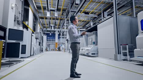 full body side view of asian male worker standing with his phone at factory digitalization, he observes by looking around before he come to concentrating with his smartphone