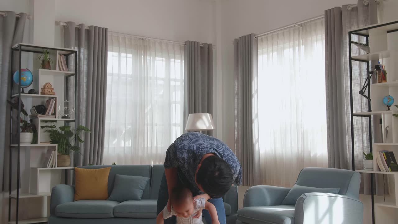 Young Asian Father And Little Son. A Man Throws Up A Toddler At Home