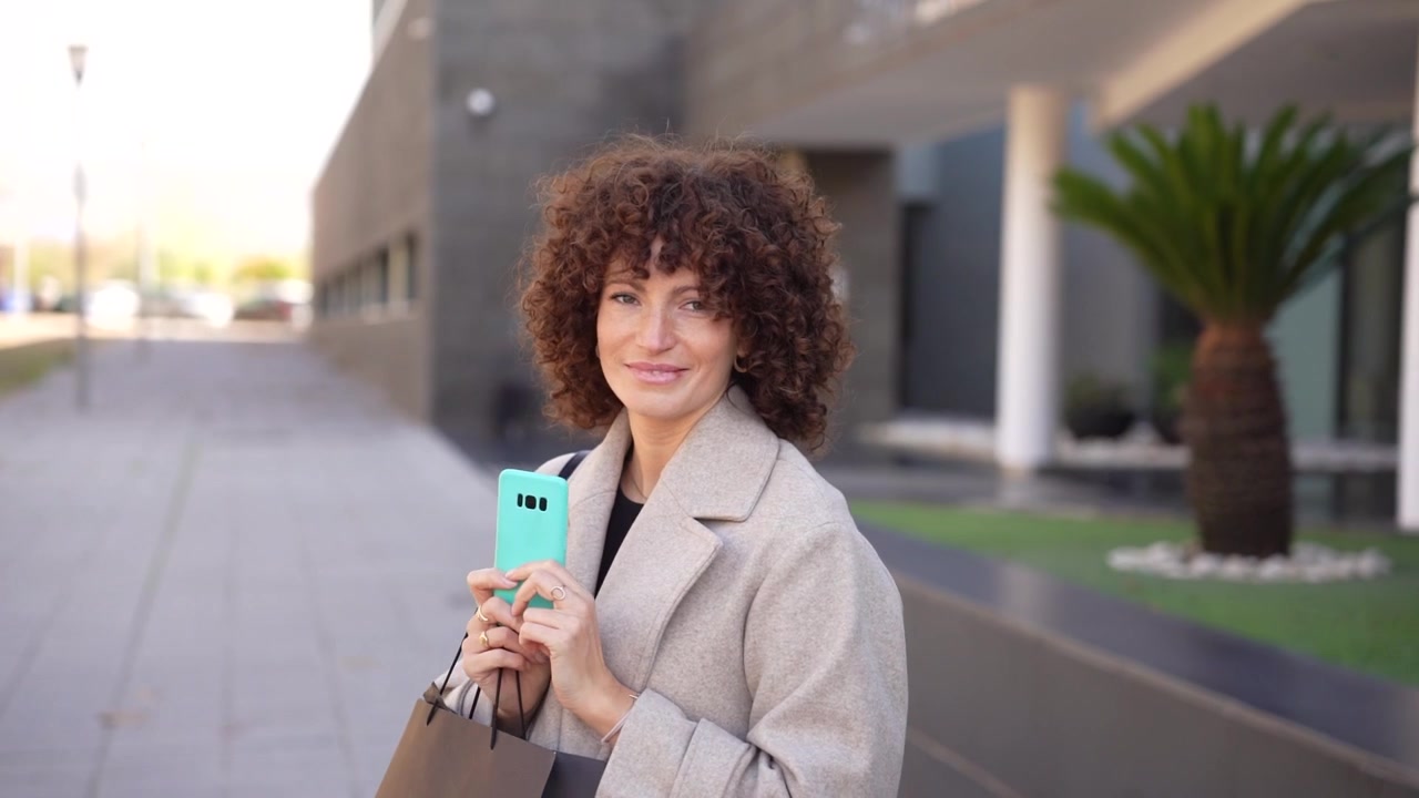 Una donna con bellissimi capelli ricci si gode il suo tempo nell'ambiente urbano all'aperto