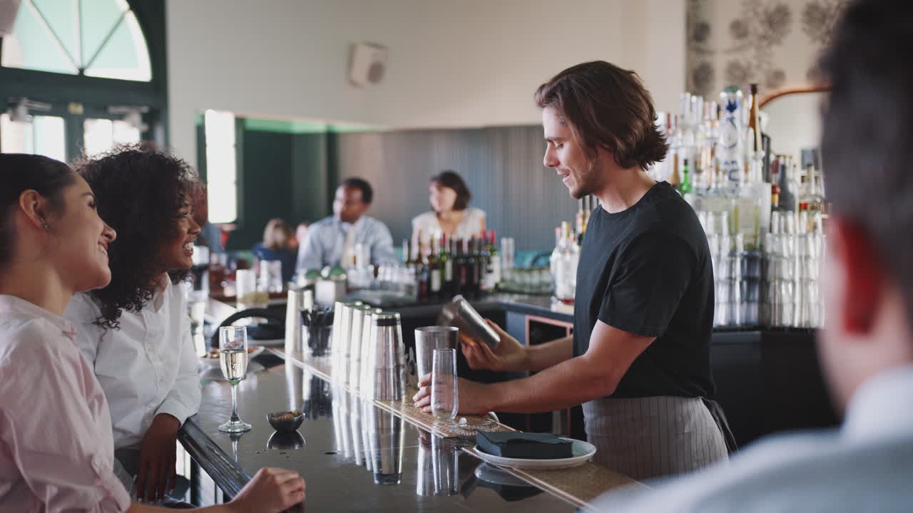barman sirviendo a dos mujeres de negocios que se reúnen para tomar bebidas después del trabajo