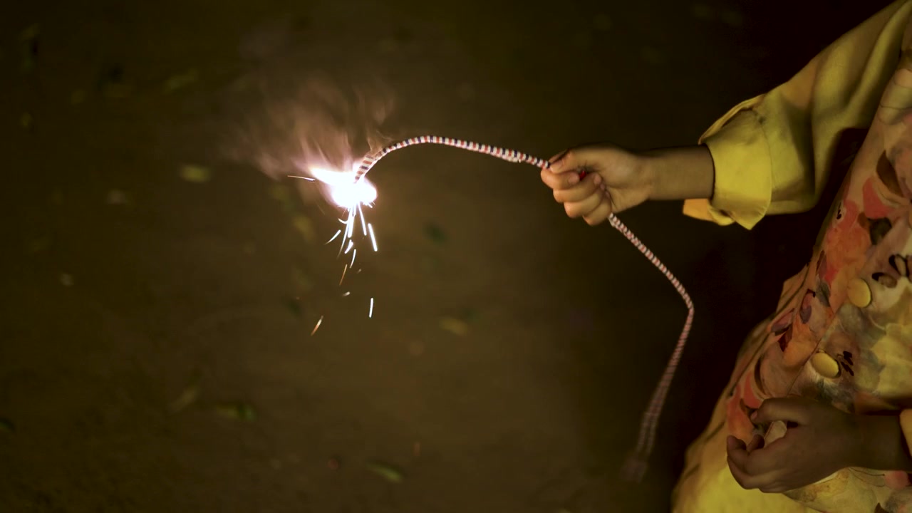 Niño sosteniendo una bengala brillante durante la celebración tradicional del Festival de Diwali por la noche