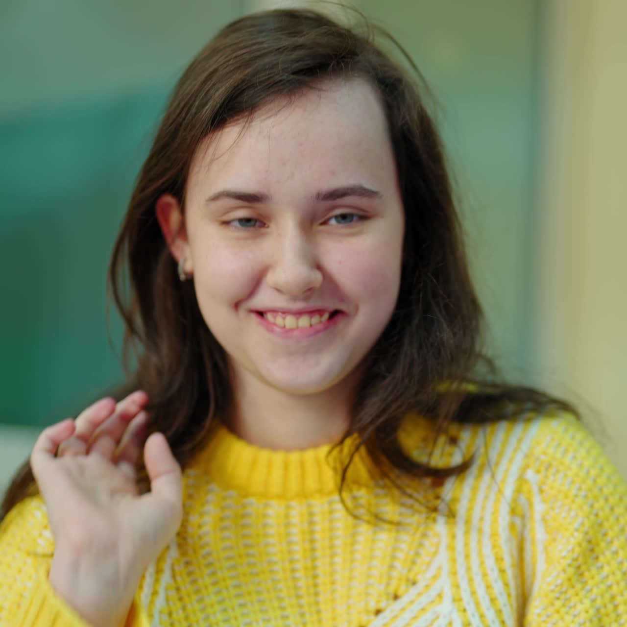 Portrait of a school girl at school. Teenage student girl in yellow sweater sitting in the classroom and studying. Education concept.