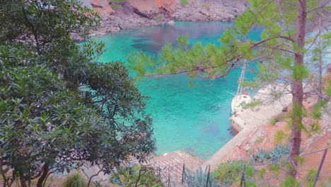 a top view of an island over the trees with crystal clear green water, surrounded with mountains