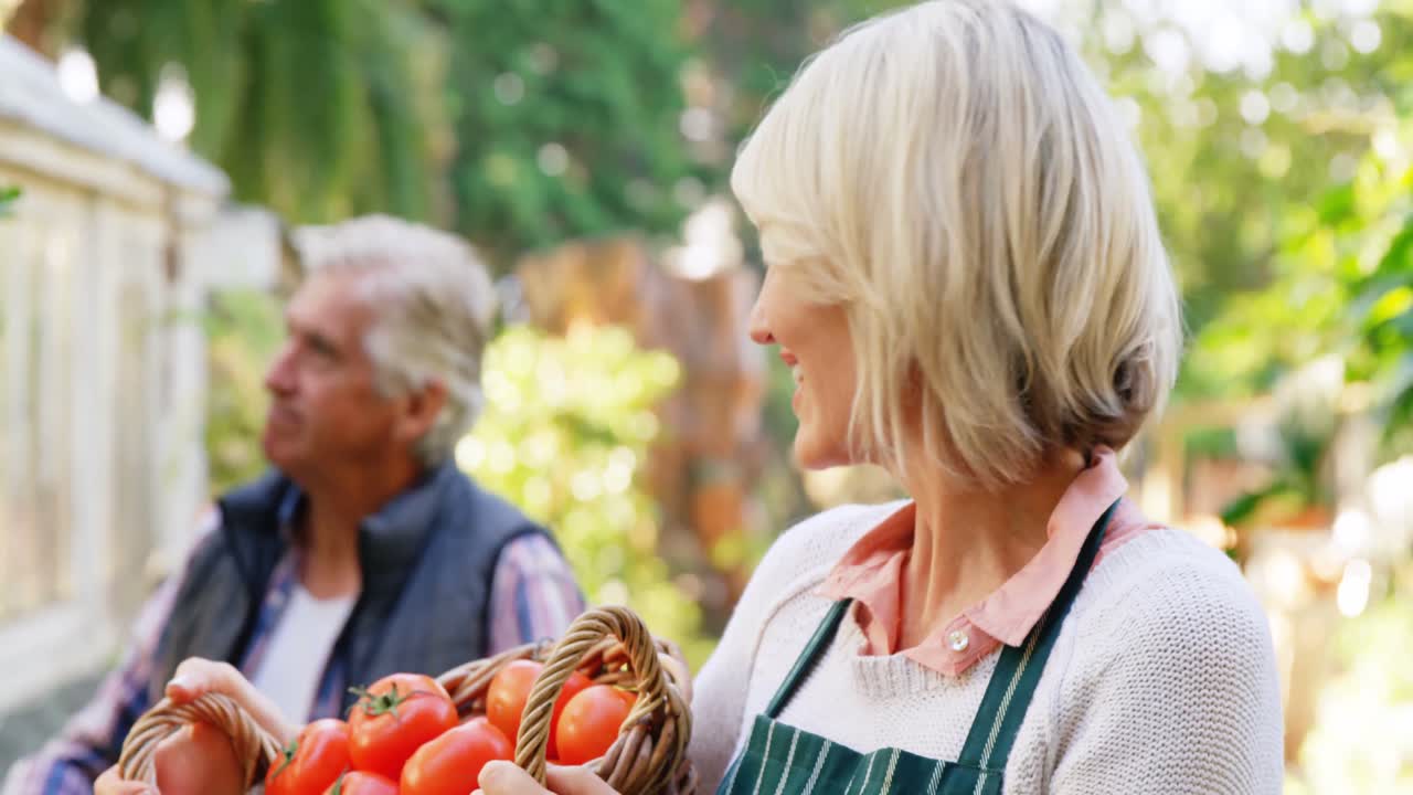 Mature woman holding wicker basket while man checking vegetables