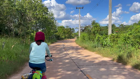 una filmación dinámica de una mujer que viaja en bicicleta con alforjas y comestibles en la parte trasera