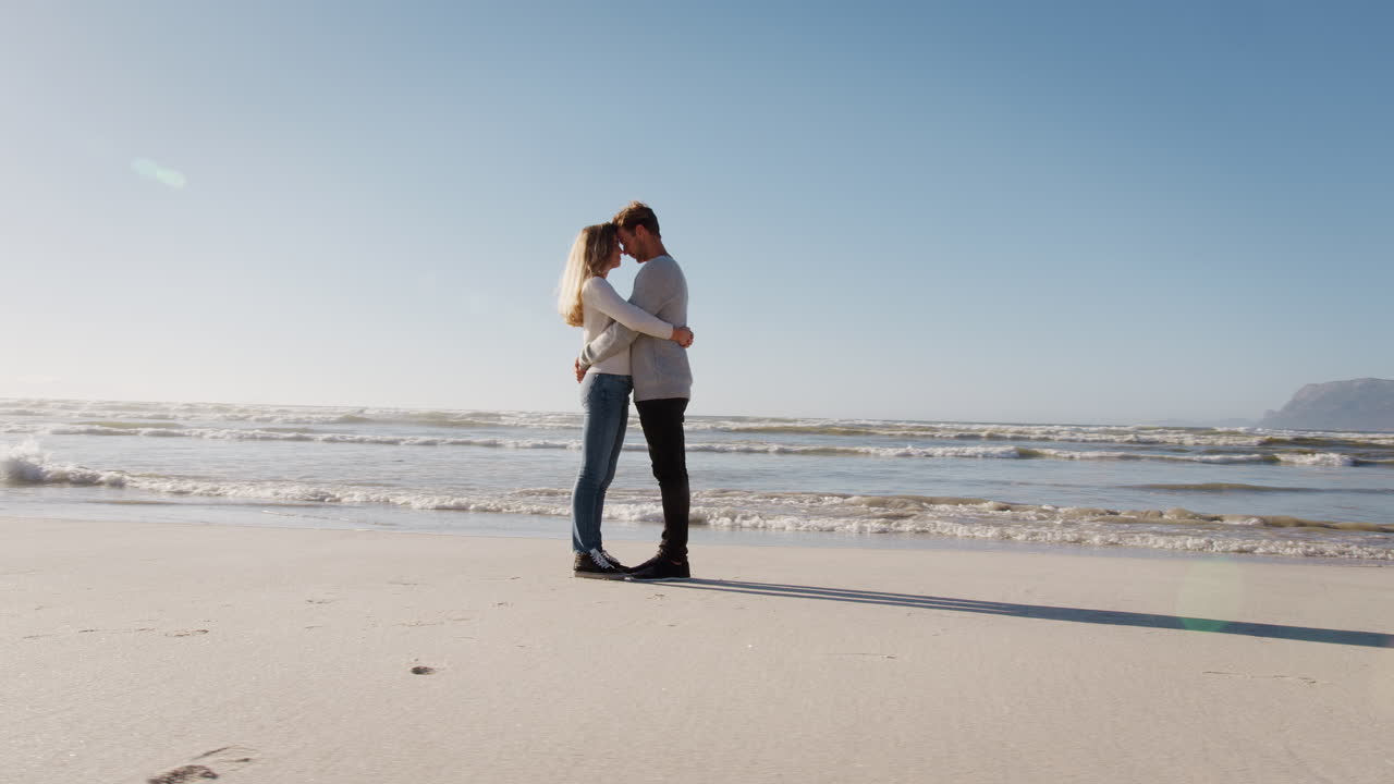 사랑하는 커플이 겨울 해변에서 함께 포옹하고 있습니다.