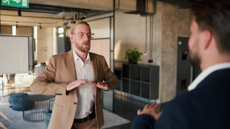 close-up shot of two male office workers practicing breathing techniques during a break between work. a blond man in a brown jacket and a white shirt and a brunette man in a blue jacket doing breathing practice