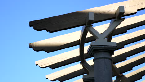 Low-angle-view-of-roof-trellis-with-pan-right-view-to-lamp-post-with-palm-trees-in-the-background