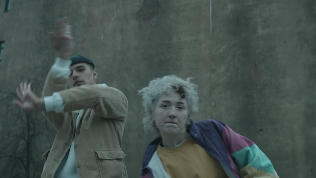 joven pareja bailando vogue a la cámara contra el viejo edificio de hormigón