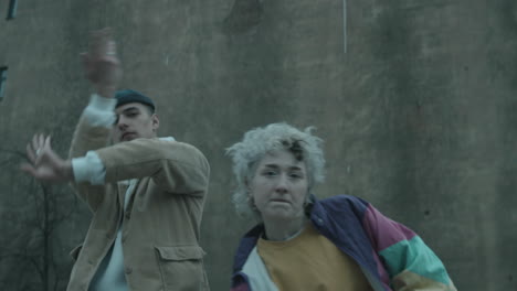 joven pareja bailando vogue a la cámara contra el viejo edificio de hormigón