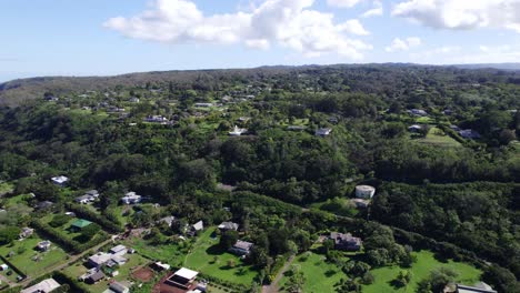 Drone-footage-of-a-coastal-town-on-the-North-Shore-of-Oahu-Hawaii-with-houses-dotting-the-lush-green-hillsides