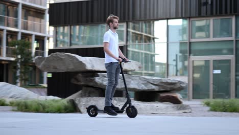 businessman rides past modern building on his e-scooter, wide shot