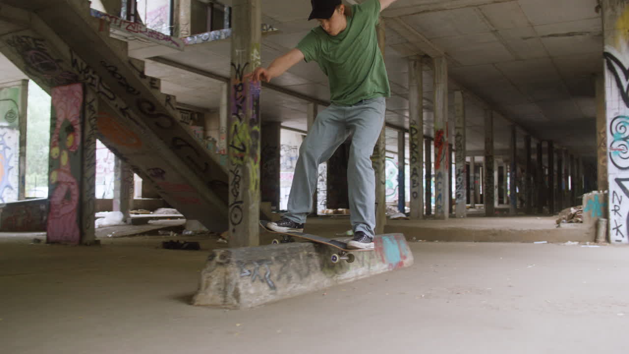 백인 소년이 폐허가 된 건물에서 스케이트보드를 타고 있습니다.