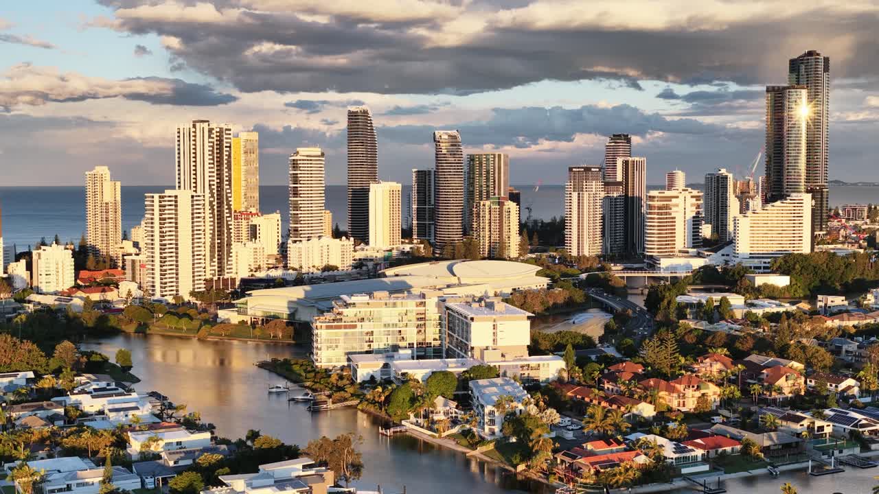 Drone footage captures Gold Coast's skyline with high-rise buildings, waterways, and vibrant sunset lighting