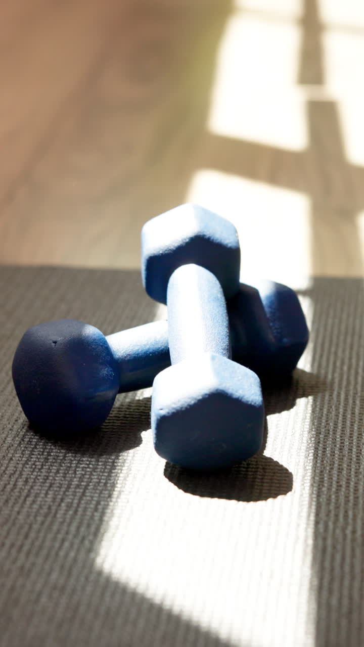 Blue Dumbbells Resting on Yoga Mat with Sunlight Shadows