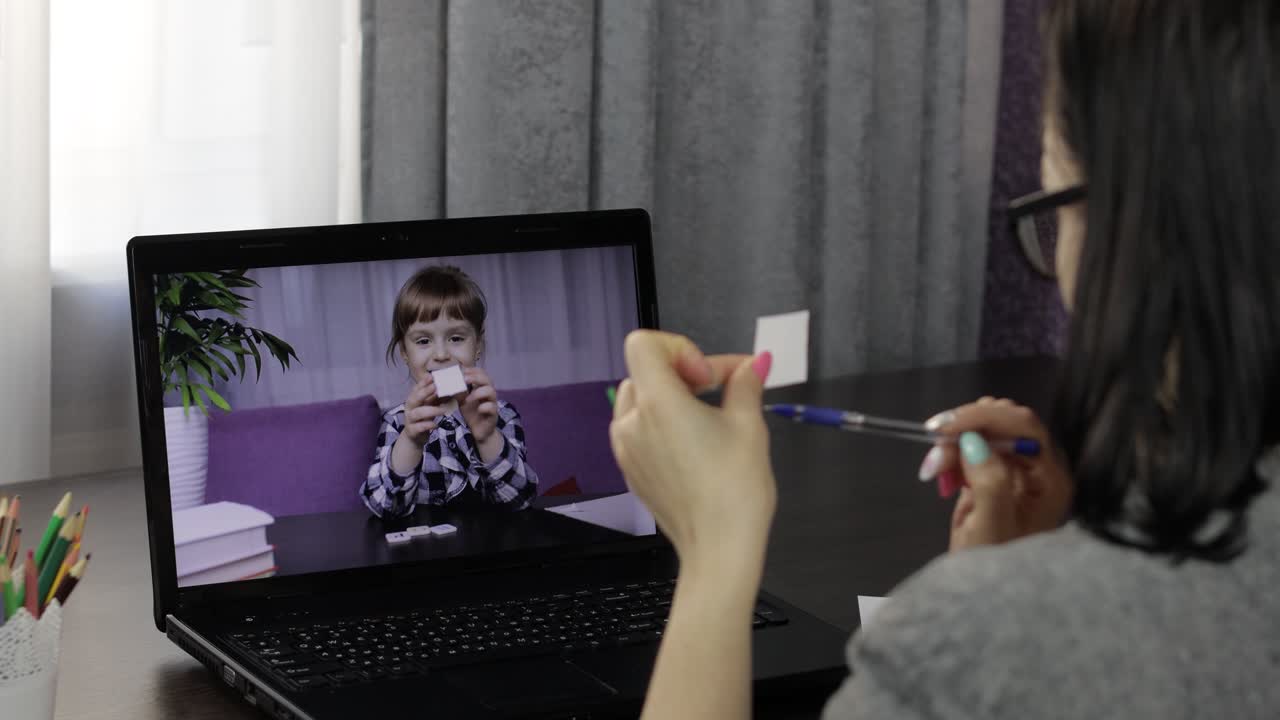Woman teacher making video call on laptop with little pupil. Distance education