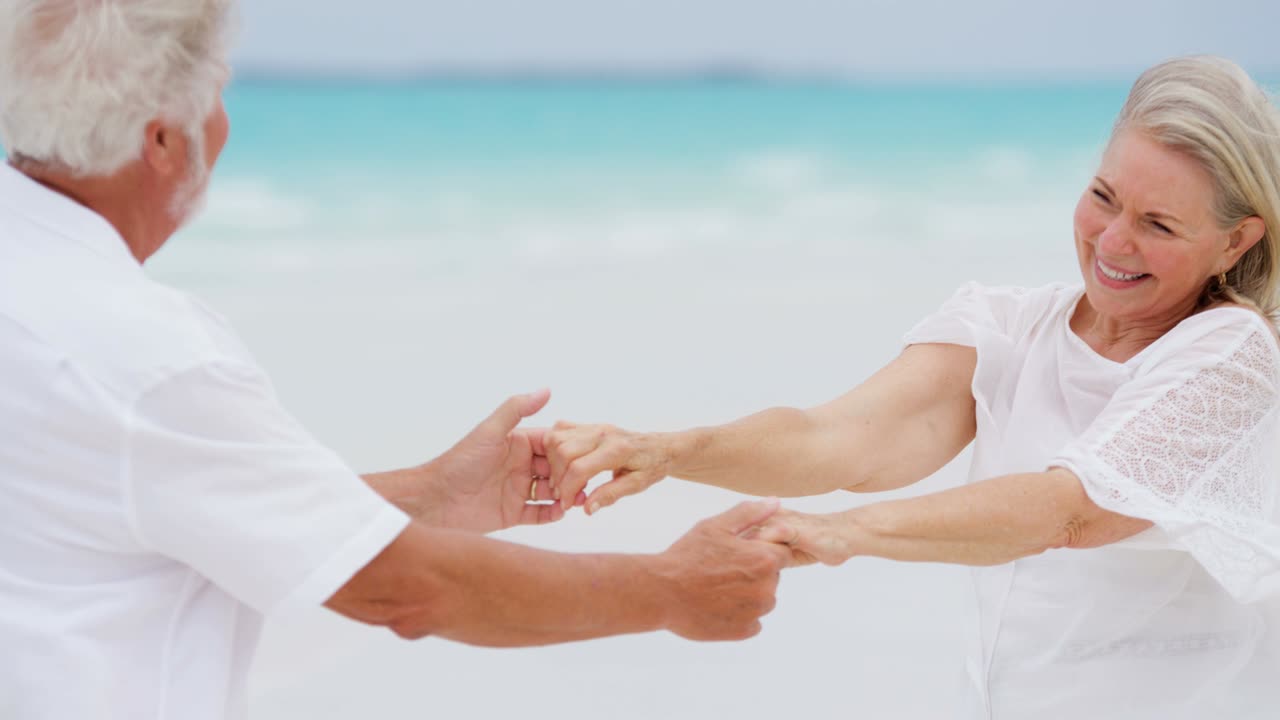 고령 백인 커플이 섬 해변에서 함께 춤을 춘다