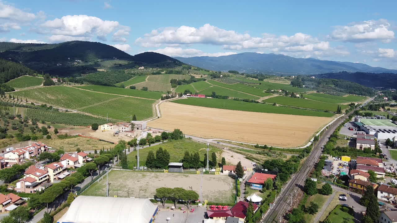 Il meraviglioso villaggio con campi verdi di piante di vigna e alte montagne sullo sfondo, sotto un cielo luminoso e nuvoloso - Veduta ampia.