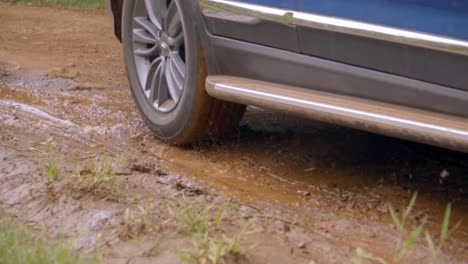 car passing through a dirt road, navigating through a mud puddle