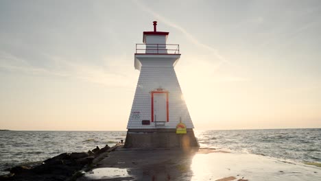 old historic lighthouse on lake huron ontario southampton, sun sets as wave splash against rocky pier