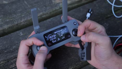 Close-up-shot-of-male-hands-piloting-drone-with-Mavic-remote-control-and-selecting-flight-settings-with-joysticks