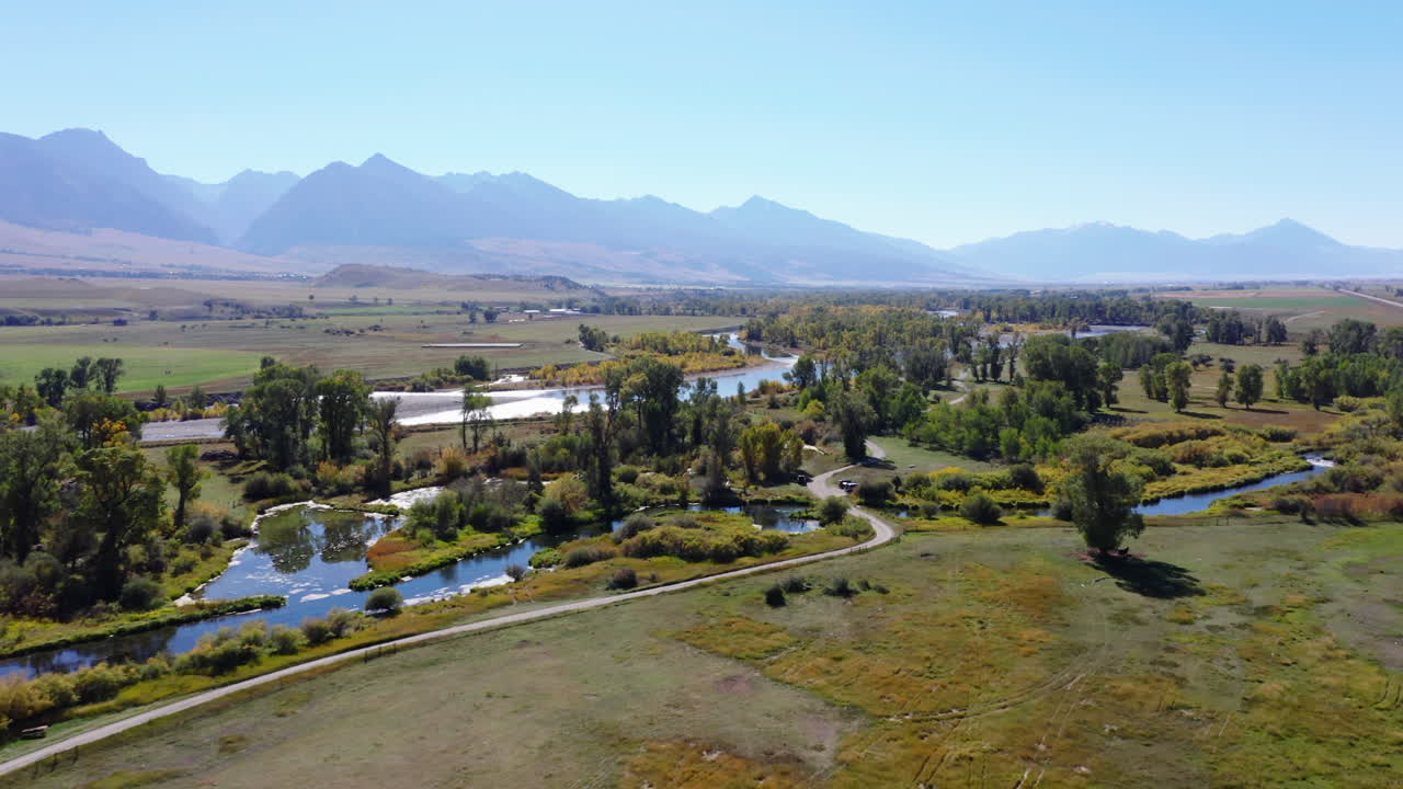 물 흐름과 나무가 있는 평평한 풍경 위로 날아갑니다.